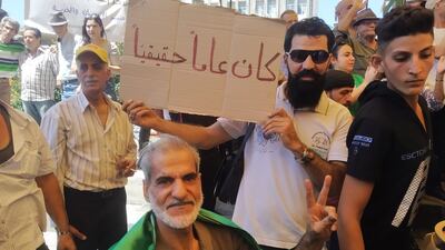 A demonstrator holds a placard that reads "it has been a real year" in the centre of the southern Syrian city of Suweida, on August 16, 2022, at the one year anniversary celebration of the protest movement against President Bashar Al Assad, in the mostly Druze province. Photo: Suhail Thubian.