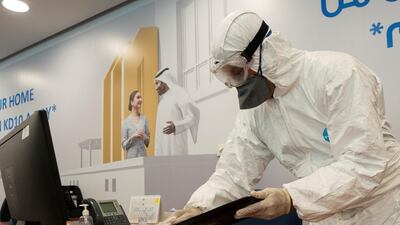 A worker wearing a protective suit wipes down a key board in a local bank in Kuwait City. Reuters