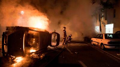 Firefighters work to put out a fire near a burning car in the Malakoff neighborhood of Nantes early on July 4, 2018. AFP