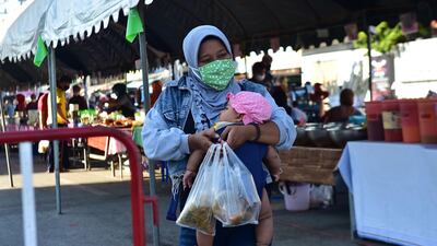 A woman holding a child walks with food in a market in Thailand's southern province of Narathiwat. AFP
