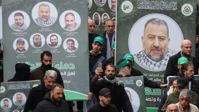 People carry placards with pictures of Mr Al Arouri during his funeral in Beirut. Reuters