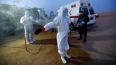 Abdelhussan Kadhim from the PMF, who volunteered to work at the cemetery, wears a protective suit as he is disinfected after the burial of a man who passed away due to coronavirus. REUTERS