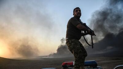 A member of the Iraqi government forces takes a position on top of a vehicle as smoke rises on the outskirts of the Qayyarah area, some 60 kilometres south of Mosul, during an operation against ISIL to retake the main hub city. Bulent Kilic / AFP