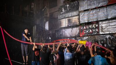 Locals help firefighters to contain a fire that broke out at a commercial complex in Dhaka, Bangladesh. AP