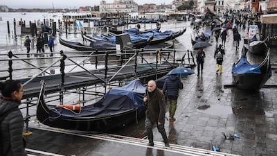 People walk past stranded gondolas washed away at Riva degli Schiavoni. AFP