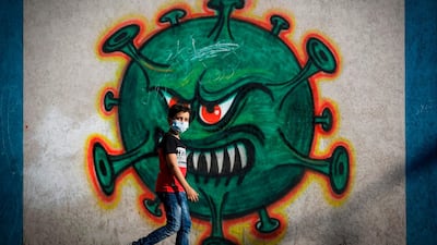 A Palestinian boy walks past street art depicting the coronavirus pandemic in Gaza city. AFP