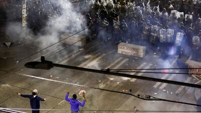 Two protesters hold their ground with their hands up as police deploy chemical agents and blast balls during a protest in Seattle, Washington. REUTERS