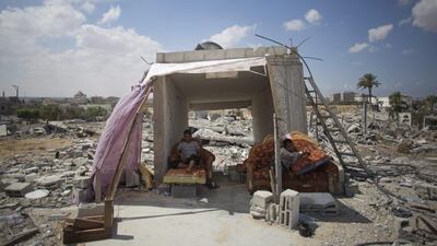 A Palestinian family takes shelter amid the rubble of a house in the town of Khan Younis in the southern Gaza Strip. Khalil Hamra / AP Photo