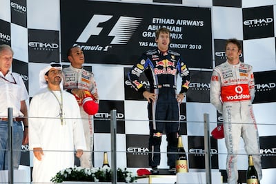 Sebastian Vettel, then of Red Bull Racing, stands atop the podium after winning the 2010 Abu Dhabi Grand Prix and clinching the drivers' title. Lewis Hamilton and Jenson Button, racing for McLaren, took second and third respectively. Andrew Henderson / The National
