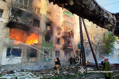 Ukrainian rescuers evacuate a woman from a burning building following a drone attack in Pavlohrad. AFP