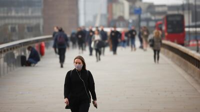 A woman wearing a protective face mask walks over London Bridge during morning rush hour, amid the coronavirus disease outbreak, in London, Britain, April 1, 2021. Reuters