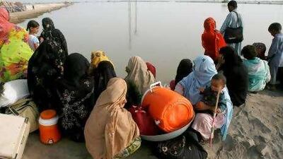 Flood victims wait for boats to cross towards their village in Pakistan's Sindh province. Below, medics from a UK-based relief team join the search for stranded people in the province.