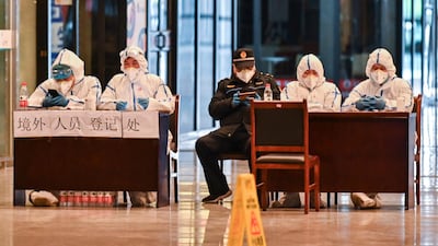 Workers in protective gear wait for passengers arriving at the railway station in Wuhan, China's central Hubei province after travel restrictions into the city were eased following two months of lockdown. AFP