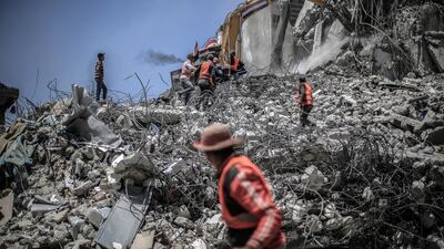 Workers collect the rubble of buildings destroyed during the May rocket attacks. Sanad Latefa for The National