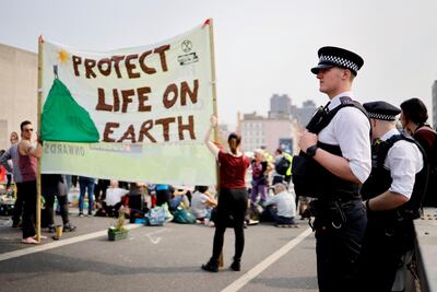 Police look on at climate change activists blockading Waterloo bridge on the third day of an environmental protest by the Extinction Rebellion group, in London on April 17, 2019. / AFP / Tolga Akmen