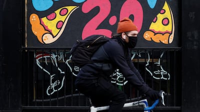 A man cycles past a mural on the boarded up window of a closed pizza restaurant in Manchester. Reuters