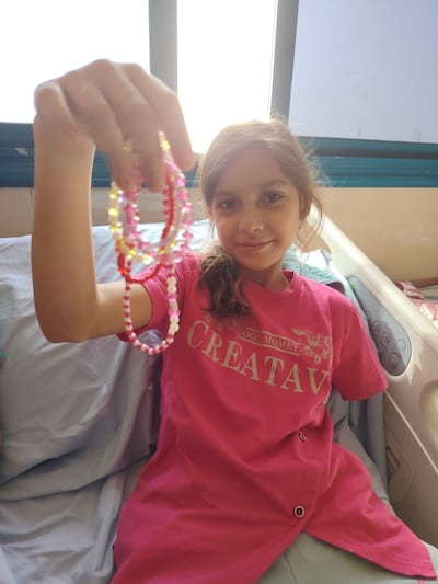 While recovering at Al Aqsa Martyrs' Hospital in Gaza, Mariam, now 10, holds up the bracelets she once wore on her left arm. Photo: Project Pure Hope