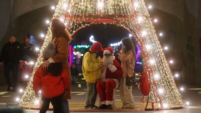 People chat with a person dressed as Santa Claus in the centre of Tbilisi, Georgia. EPA