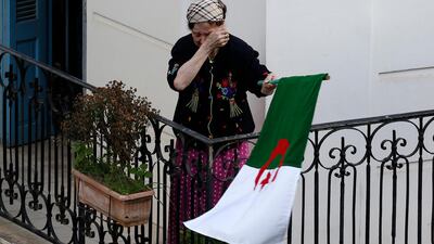 A woman wipes her face while carrying a national flag in Algeria. AP Photo