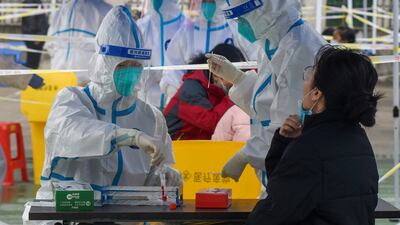 Medical workers in protective suits collect swabs from residents at a Covid-19 testing site in Ningbo, China. Reuters