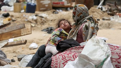 A Palestinian mother holds her sleeping child after fleeing Rafah due to an Israeli military operation. Reuters