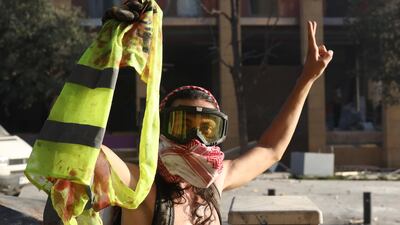 A Lebanese anti-government protester flashes a victory sign and holds a blood-stained yellow jacket of a fellow protester during clashes with riot police. EPA