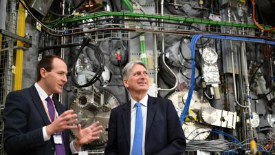 Britain's Chancellor of the Exchequer Philip Hammond listens to Ian Chapman, Chief Executive of the UK Atomic Energy Authority, in front of nuclear fusion scientific equipment, as he marks the publication of the UK gross domestic product (GDP) first quarterly estimate during a visit to the Culham Science Centre in Abingdon, Oxfordshire, Britain May 10, 2019. REUTERS