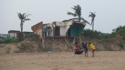 Former inhabitants of the of Podemepta village sit at an abandoned house. The houses once belonged to a prosperous fishermen community but are now a testimony of widespread devastation caused by climate change.