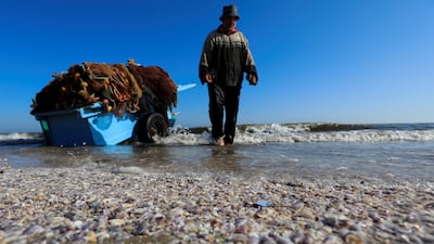 An Egyptian fisherman walks next to sand and seashells in front of his boat during low tide of water along a beach in the Red Sea shore at Port Said city, northeast of Cairo, Egypt May 27, 2022. REUTERS / Amr Abdallah Dalsh