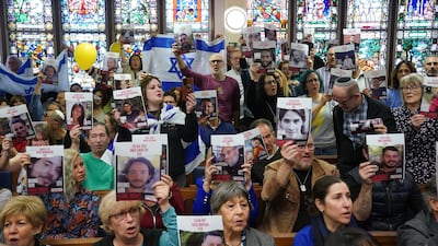 Family members of the hostages hold up images of those taken on October 7. PA