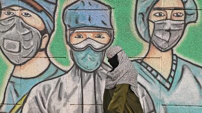 A person walks past a wall mural depicting frontline Covid-19 workers wearing face masks along a road in New Delhi, India, on March 21, 2021. AFP