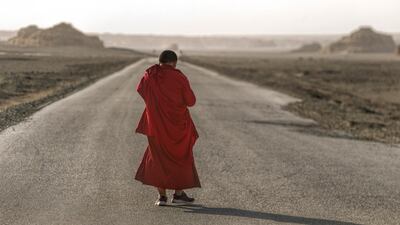 A Buddhist monk walks on the desert road.