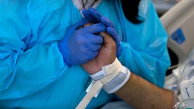 Patty Trejo, 54, holds the hand of her intubated husband, Joseph, in a Covid-19 unit at St. Jude Medical Center, in Fullerton, California. AP Photo