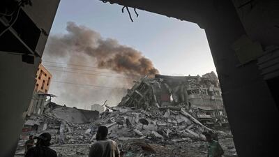 People gather amidst the rubble in front of Al-Sharouk tower that collapses after being hit by an Israeli air strike, in Gaza City, on May 12, 2021. An Israeli air strike destroyed a multi-storey building in Gaza City today, AFP reporters said, as the Jewish state continued its heavy bombardment of the Palestinian enclave. AFP