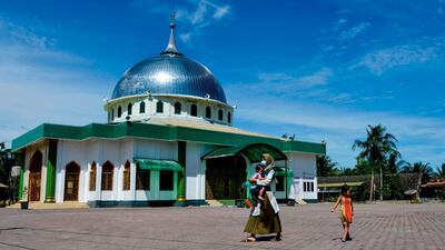 A mother walks away while holding her child, who earlier received tuberculosis and polio vaccines, at an integrated services post in Banda Aceh. AFP