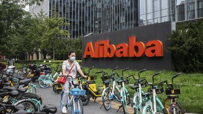 A cyclist wearing a protective mask rides past the Alibaba building in Beijing. Investors are swapping their US-listed Alibaba shares with those in Hong Kong. Bloomberg