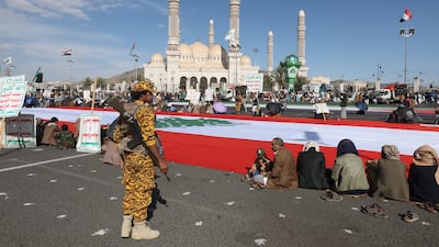 An armed Houthi soldier stands guard as Houthi supporters gather around a large Lebanese flag during a rally in Sanaa, Yemen, on November 1. EPA