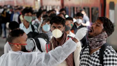 A health worker collects a swab sample from a traveller at a railway station to test for the coronavirus before allowing him to enter Mumbai, India. AP