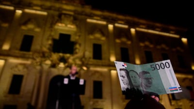 A protester holds up a fake banknote showing the faces of Malta's Prime Minister Joseph Muscat and his former chief of staff Keith Schembri. AP