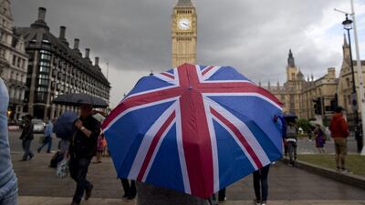 A pedestrian shelters from the rain beneath a Union flag themed umbrella by the Big Ben clock face and the Elizabeth Tower at the Houses of Parliament in London on June 25, 2016. AFP