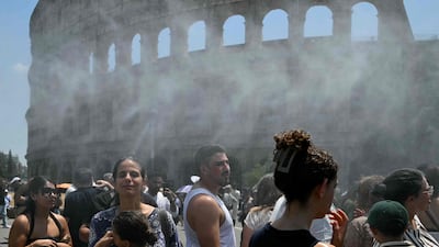 People try to cool down in the spray from portable misting machines near the Colosseum in Rome, Italy. AFP