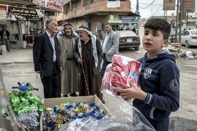 A boy sets out Christmas decorations at a shop in Qaraqosh, Iraq, 20 December 2017. Photo: Campbell MacDiarmid