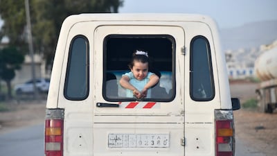 A Syrian girl looks out of the rear window of a vehicle transporting families celebrating Eid Al Fitr in Afrin. AFP