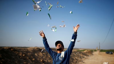 A Palestinian man throws leaflets dropped by the Israeli military during a protest against the US embassy move to Jerusalem and ahead of the 70th anniversary of Nakba, at the Israel-Gaza border, east of Gaza City. Mohammed Salem / Reuters