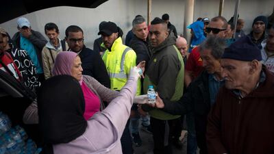 Two women give water to people as they wait to cross the border from Ceuta to Morocco. AFP