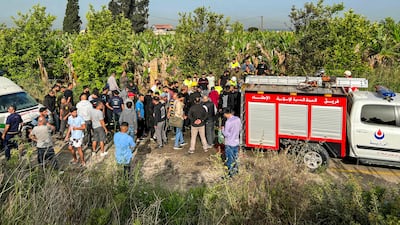 People gather at the site of an Israeli strike on a car near Tyre, Lebanon, on Tuesday, in which a Hezbollah operative was killed. AFP