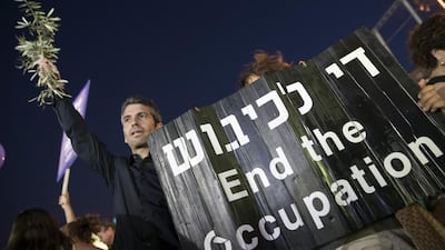 An Israeli left-wing supporter holds a banner during a mass demonstration against 50 years of occupation in Tel Aviv. Photo: Jack Guez / AFP