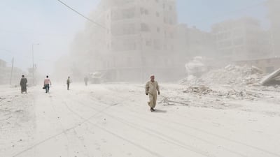 Syrians walk amid dust following a reported barrel-bomb attack by Syrian government forces in the Tariq al-Bab neighbourhood in the northern city of Aleppo. Zein Al-Rifai / AFP