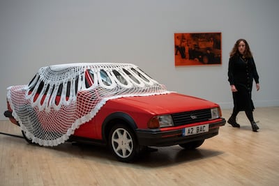Jasleen Kaur's work explores dual identity through everyday objects, including a red Ford Escort car covered in a huge doily. AP