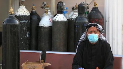 An Iraqi man waits next to oxygen bottles for his wife who is a patient with COVID-19 at the Ibn Al-Khatib Hospital in Baghdad, on April 25, 2021, after a fire erupted in the medical facility reserved for the most severe coronavirus cases. - At least 23 people died when a fire broke out in a coronavirus intensive care unit in the capital of Iraq, a country with long-dilapidated health infrastructure facing mounting COVID-19 cases. (Photo by AHMAD AL-RUBAYE / AFP)